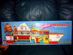 a barbie doll sitting on top of a couch in front of a box that says barbie's dream boat