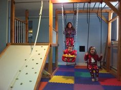 two children on swings in a play room