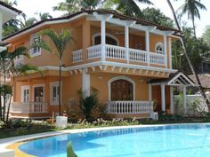 a house with a pool in front of it and palm trees around the pool area