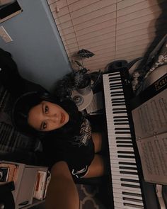 a woman standing next to a piano in a room