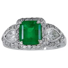 Features a vibrant emerald cut green emerald, accented with pear shape diamonds on either side. Center and side diamonds surrounded by a brilliant diamond halo. Set in 18k white gold. Size 6 US (sizable) Dimensions: 0.38 in x 0.78 in Engagement Rings Green, Three Stone Engagement Rings Emerald, Three Stone Engagement Rings Halo, Engagement Rings Emerald, Halo Engagement Ring Emerald, Victorian Engagement Rings, Pear Cut Engagement Rings, Zambian Emerald, Three Stone Engagement