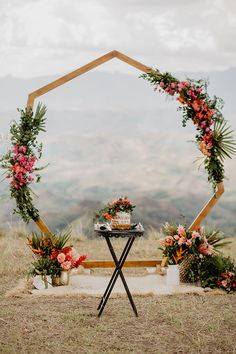 an outdoor ceremony setup with flowers and greenery on the table, in front of mountains