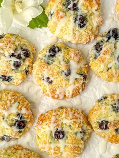 blueberry muffins with white icing and fresh flowers on the side, ready to be eaten