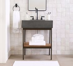 a bathroom with a sink, mirror and towels on the shelf in front of it