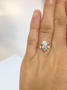 a woman's hand with a diamond ring on top of her left hand,