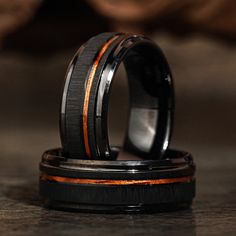 two wedding rings with orange and black wood inlays sitting on top of each other