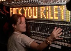 a woman standing in front of a sound board with her hands out to the side