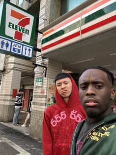 two young men standing in front of a seven eleven store on the corner of an urban street