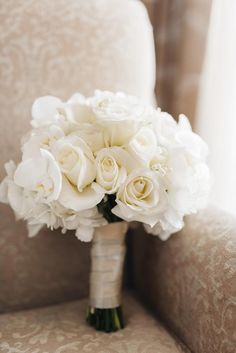 a bouquet of white flowers sitting on top of a couch next to a chair in a room