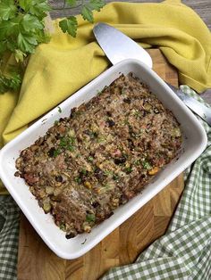 a casserole dish on a cutting board with a knife and parsley in the background