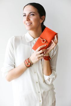 a woman holding an orange purse in her hands