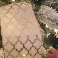 someone is holding up an ornament in front of a christmas tree