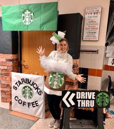 a woman standing next to a starbucks sign and holding her hands up in the air