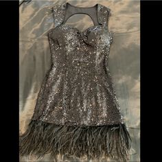 a dress with feathers on the bottom and sequins on the bottom, sitting on a bed