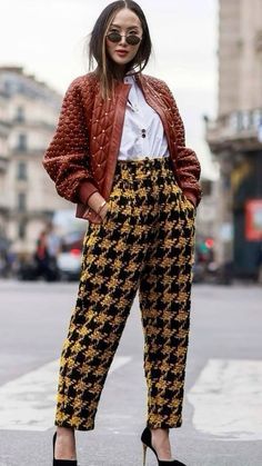 a woman standing in the middle of a street wearing high heels and an orange jacket