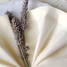 a bunch of lavender flowers sitting on top of a white cloth covered tablecloth with an alarm clock in the background