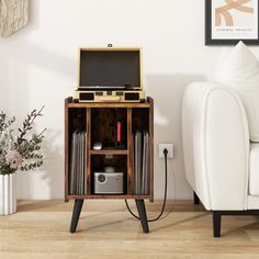 an old record player sitting on top of a wooden stand next to a white couch