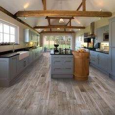 a large kitchen with wooden floors and gray cabinetry, along with an island in the middle