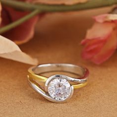 two tone gold and silver wedding rings with a round diamond in the center on a brown background