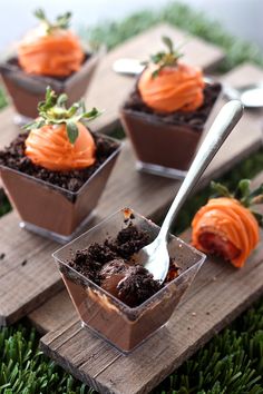 four desserts in small glass dishes with spoons on wooden boards and green grass