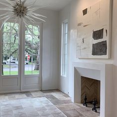 an empty room with a fireplace and two large windows