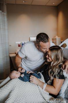 a man and woman cuddle while holding a baby in their arms on a bed