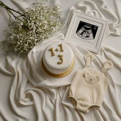 a baby's first birthday cake with a teddy bear on the table next to it