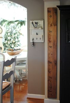 a room with a tall wooden ruler on the wall next to a chair and table