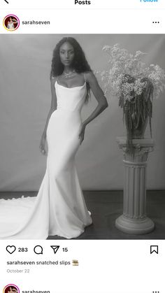 a black and white photo of a woman in a wedding dress standing next to a vase with flowers