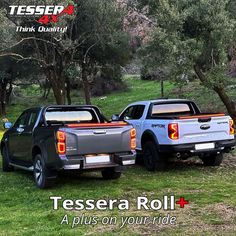 two pick up trucks parked next to each other in the grass with trees behind them