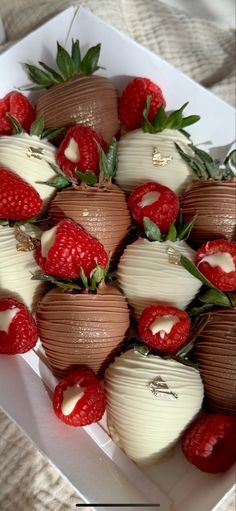 chocolate covered strawberries and raspberries are arranged in a square white dish on a table