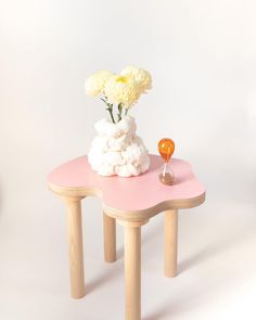 a pink table with flowers on it and an orange object sitting on the top one