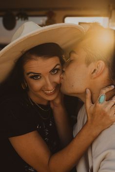 a man and woman kissing each other while wearing hats