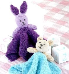 two crocheted stuffed animals sitting next to each other on a pink and white checkered blanket