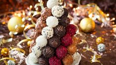 a tower of chocolate covered strawberries and raspberries on a table with christmas decorations in the background