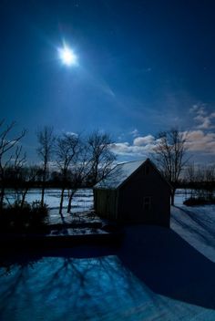 the moon shines brightly over a snowy landscape