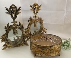 two ornately decorated mirrors sitting next to each other on a white tableclothed surface