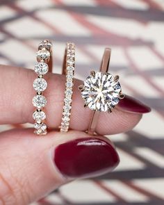 a woman's hand holding three different types of engagement rings and diamond bands on her finger