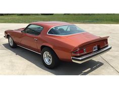 an orange muscle car parked in a parking lot