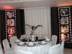 a table with white chairs and pictures on the wall behind it is set up for a formal function