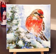 a painting of a red bird sitting on top of a wooden easel next to a christmas tree