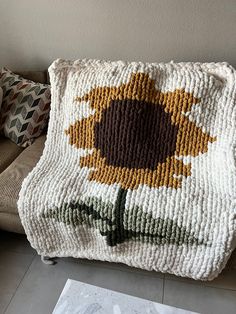 a crocheted sunflower pillow sitting on top of a couch next to a coffee table