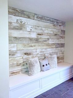 a bench with two pillows on it in front of a wood paneled accent wall