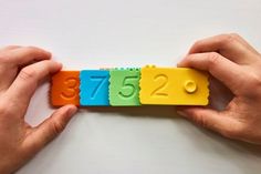 two hands holding colorful blocks with numbers on them