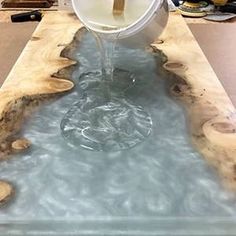 a white toilet sitting on top of a wooden table next to a bucket filled with water