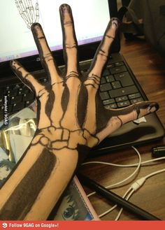 a person's hand painted with black and white paint on their left arm next to a laptop computer