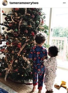 two children standing in front of a christmas tree