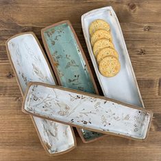 four serving trays with crackers in them on a wooden table next to each other