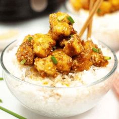 a bowl filled with rice topped with meat and green onions next to chopsticks