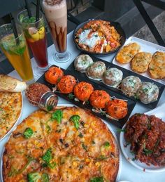 a table topped with lots of different types of food next to drinks and desserts